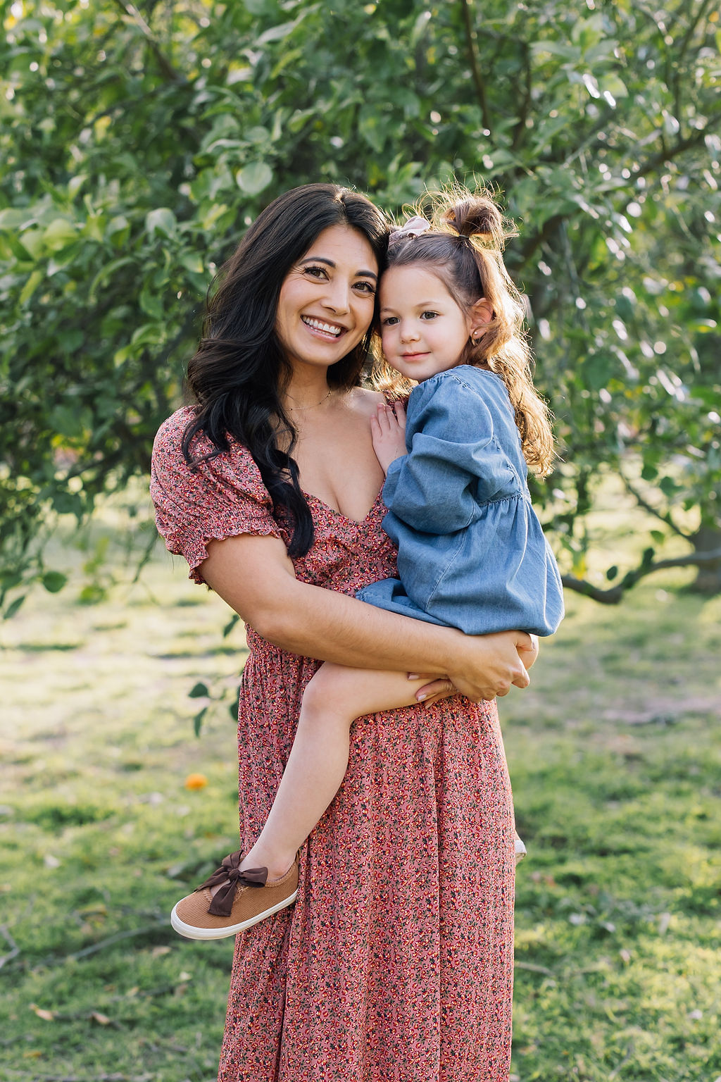 A happy toddler sits on mom's hip while exploring a park before visiting pumpkin patches santa clarita