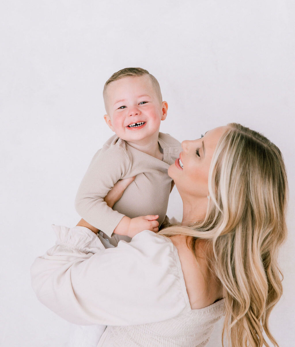 A pregnant mom lifts her giggling toddler son in a studio before some prenatal yoga in santa clarita