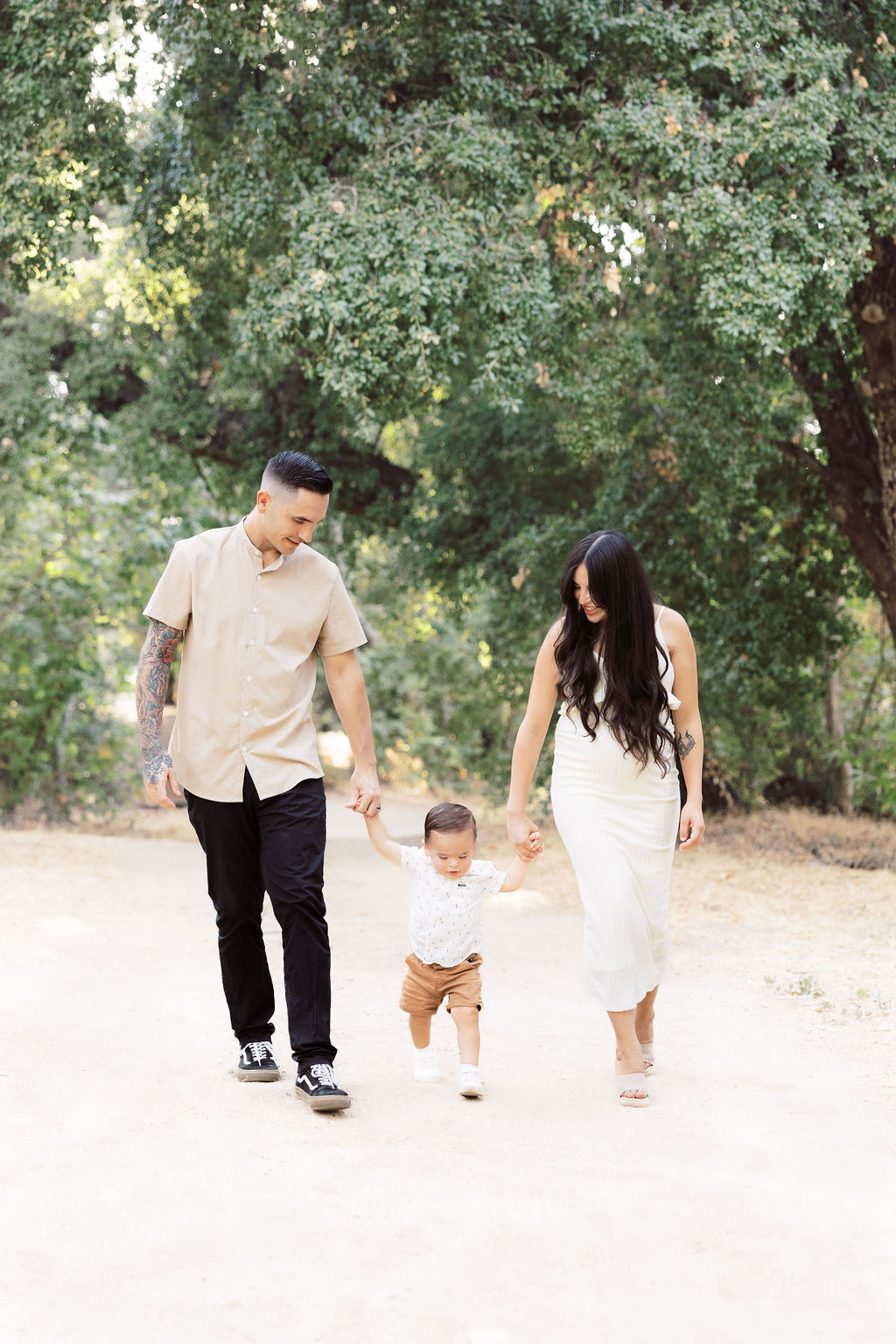 A happy family of 3 walk in a park trail holding hands at sunset before exploring pelvic floor therapy in santa clarita