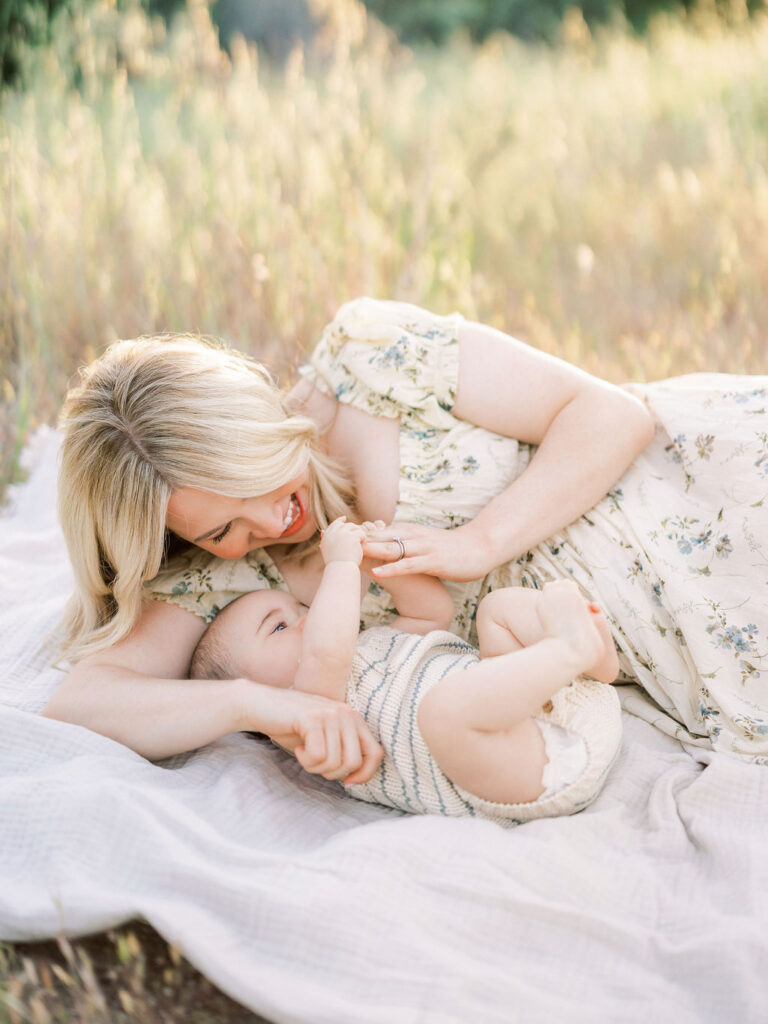 Mother playing with her baby on a blanket during a peaceful outdoor spring session.