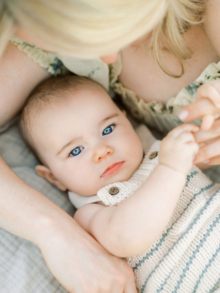 Baby looking at the camera while resting beside mom during a quiet outdoor family moment.