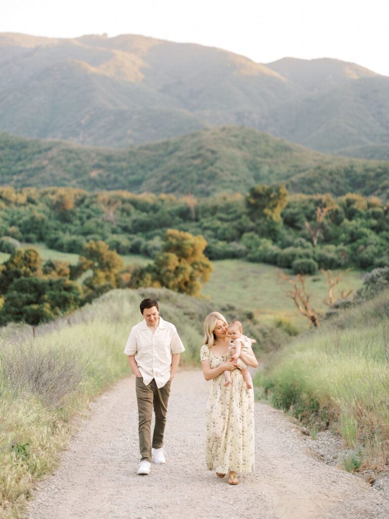 Family walking along a scenic trail with rolling hills in the background during golden hour.