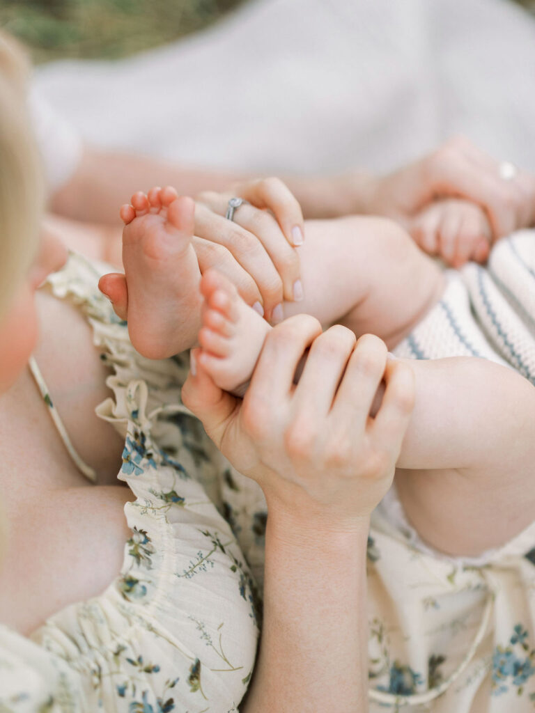 Close up of a mother gently holding her baby’s feet during an outdoor family session.