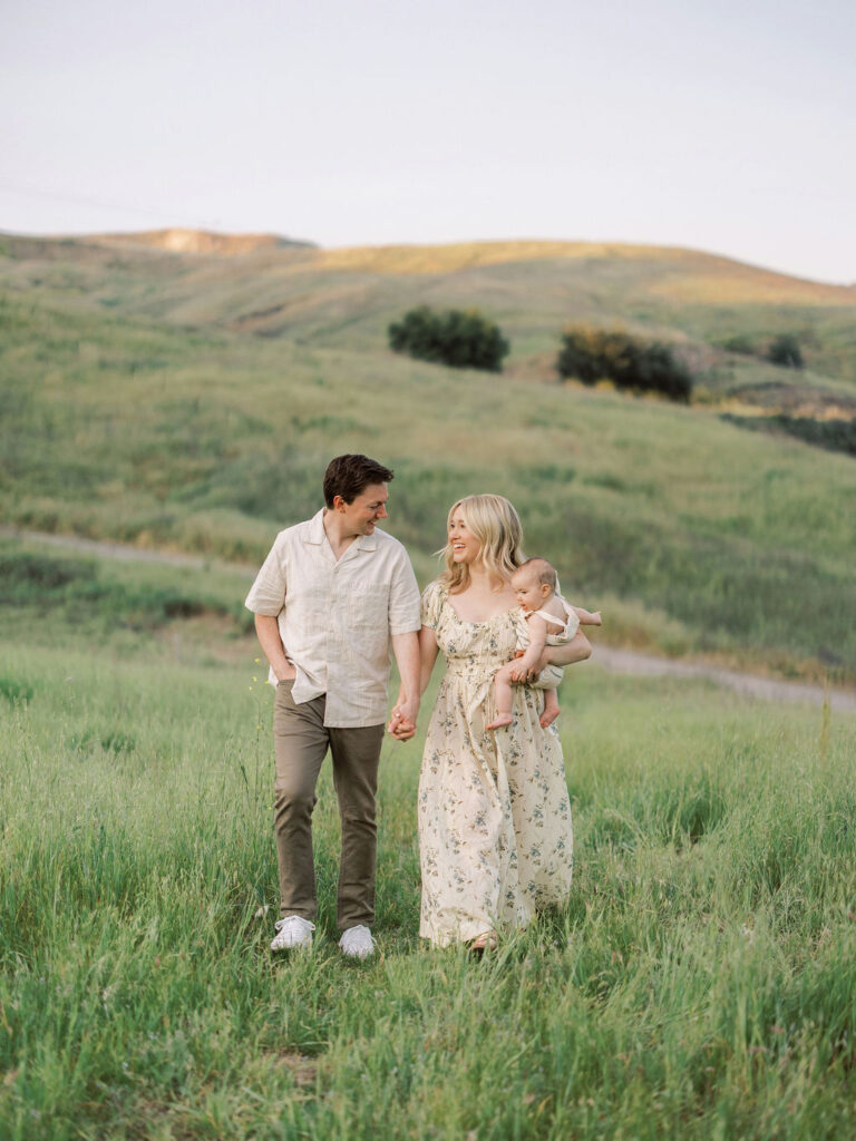 Family walking through a green spring field during golden hour in Santa Clarita.