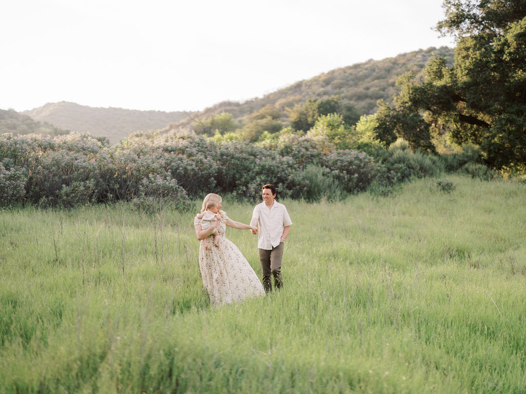 Parents walking together through a sunlit field during a family photo session in Santa Clarita, California.