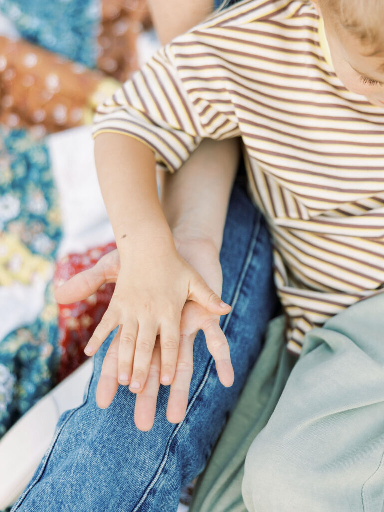 Close up of parents holding their toddler’s hands during a relaxed family photography session