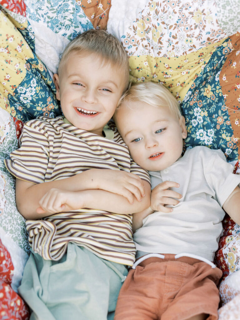 Young siblings cuddling together on a blanket during a playful Santa Clarita family session