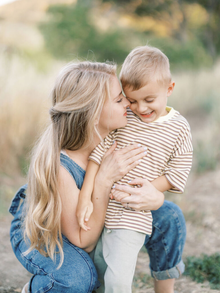 Mom cuddling her smiling toddler during relaxed family photos with toddlers