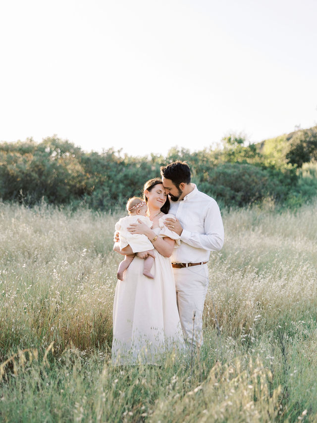 Parents cuddling their baby during a relaxed outdoor family photography session