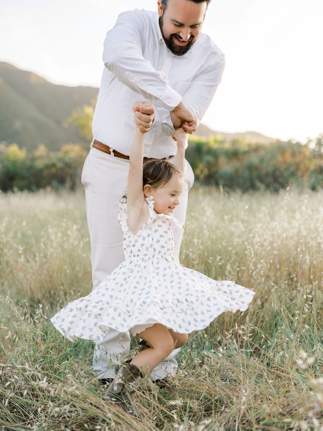 Dad twirling his daughter during a playful family photo session outdoors