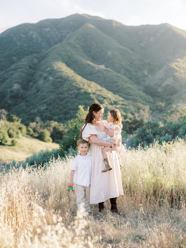 Mom holding her daughter with her young son during family photos outdoors