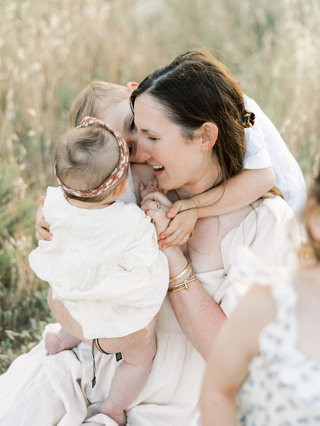 Mom laughing while cuddling her three children outdoors