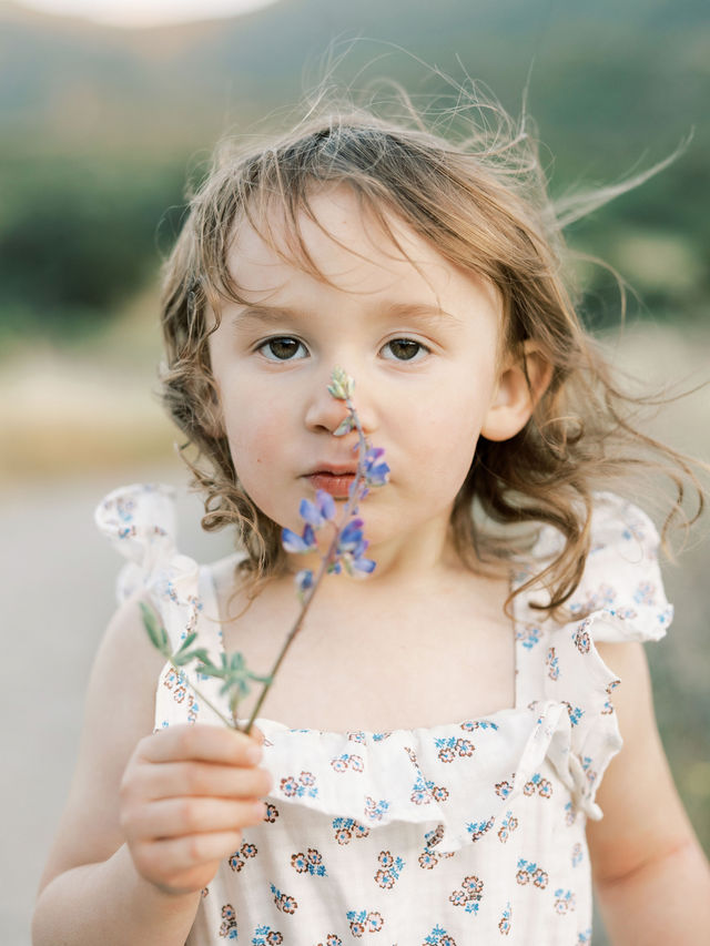 Young girl holding wildflowers during an outdoor family photo session in Santa Clarita