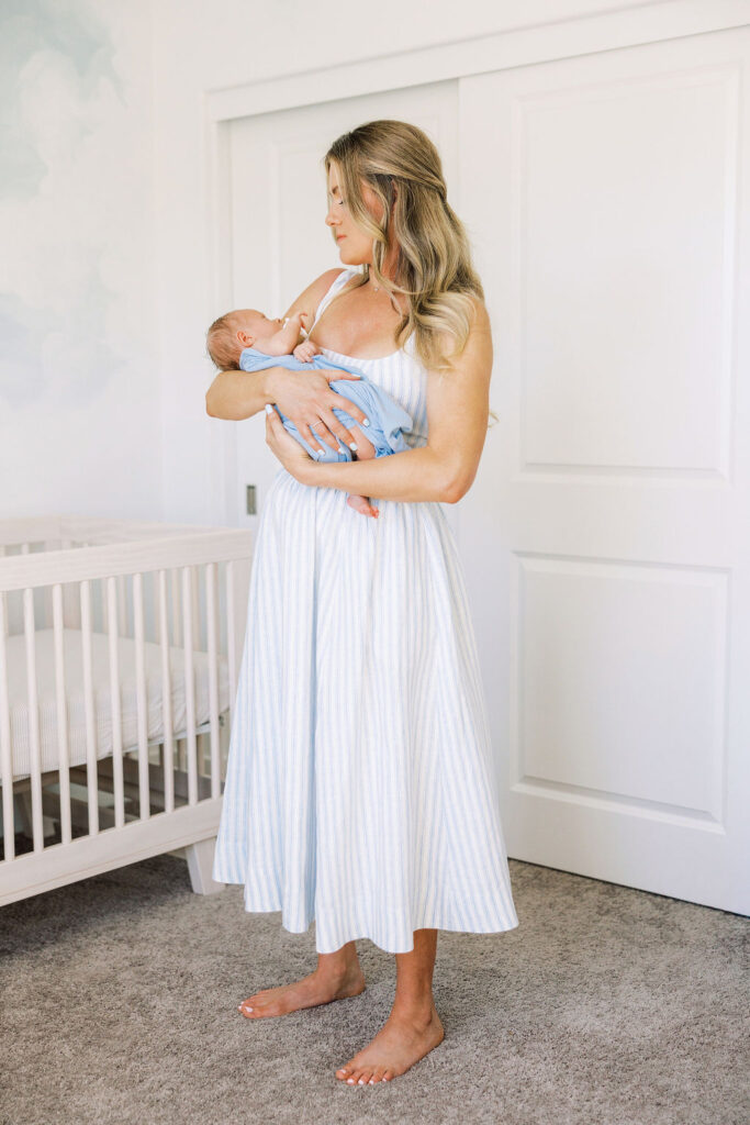 Mother holding her newborn in a softly lit room at home.