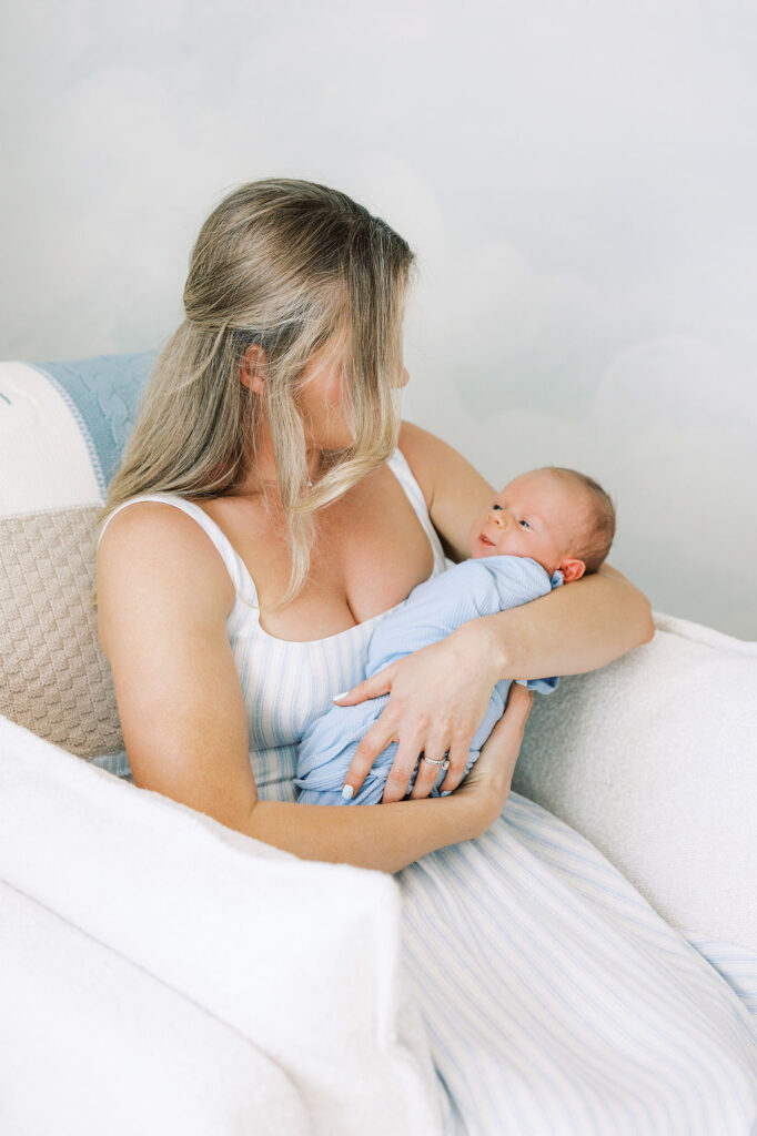 Mother looking down at her newborn while holding the baby close.