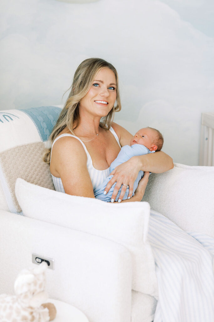 Mother holding her newborn while sitting together in the nursery.