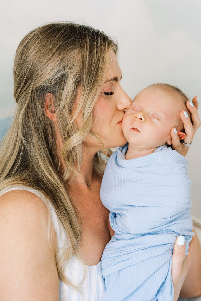 Mom kissing her newborn while dad holds the baby close.