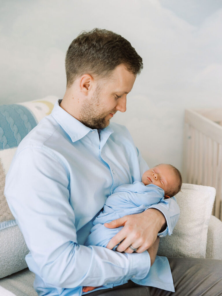 Dad looking down at his newborn during in-home newborn photography Santa Clarita.