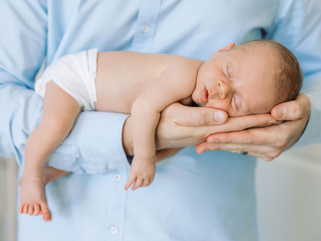Close-up of a newborn’s tiny feet resting in a parent’s hands.