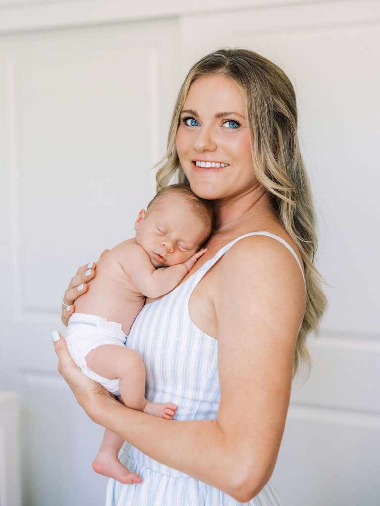 Smiling mother holding her newborn baby in a light filled nursery.