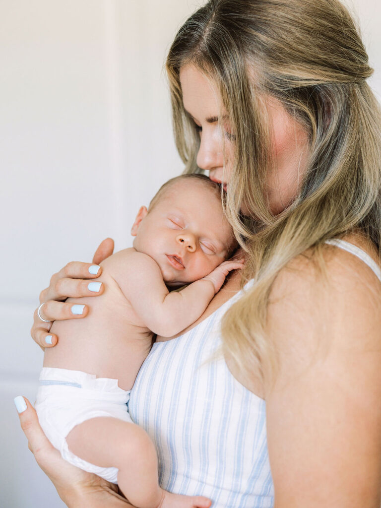 Mom holding her sleeping baby during in-home newborn photography Santa Clarita.