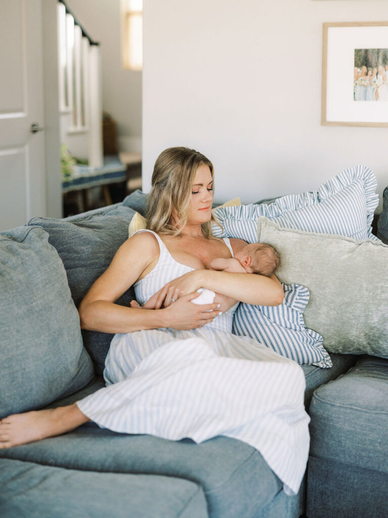 Mom cuddling her newborn while sitting on the bed at home.