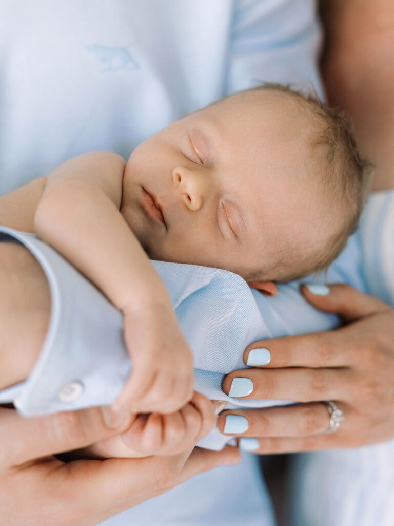Sleeping newborn resting peacefully in a parent’s arms.