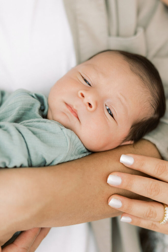 Newborn baby wrapped in a soft green blanket during a lifestyle session