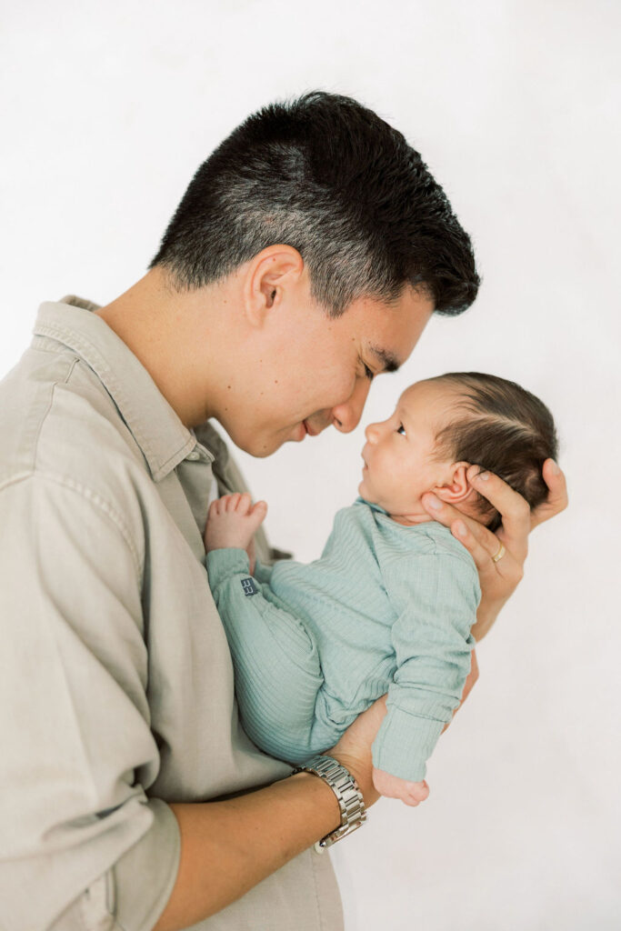 Dad leaning close to his newborn baby during a studio session