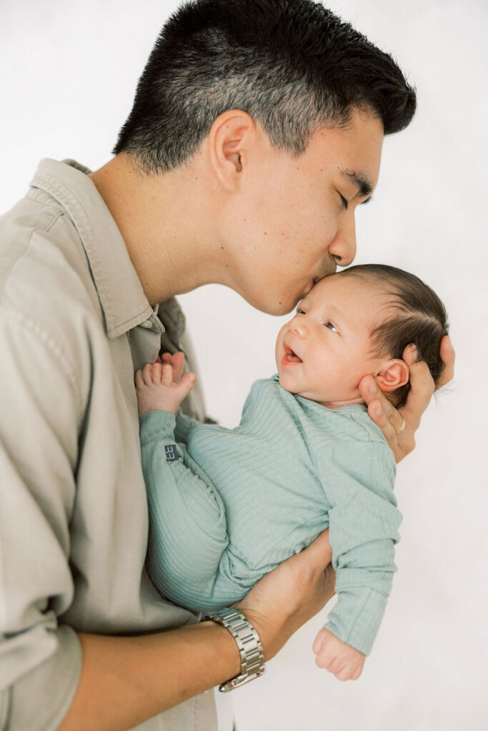 Father holding and kissing his newborn baby