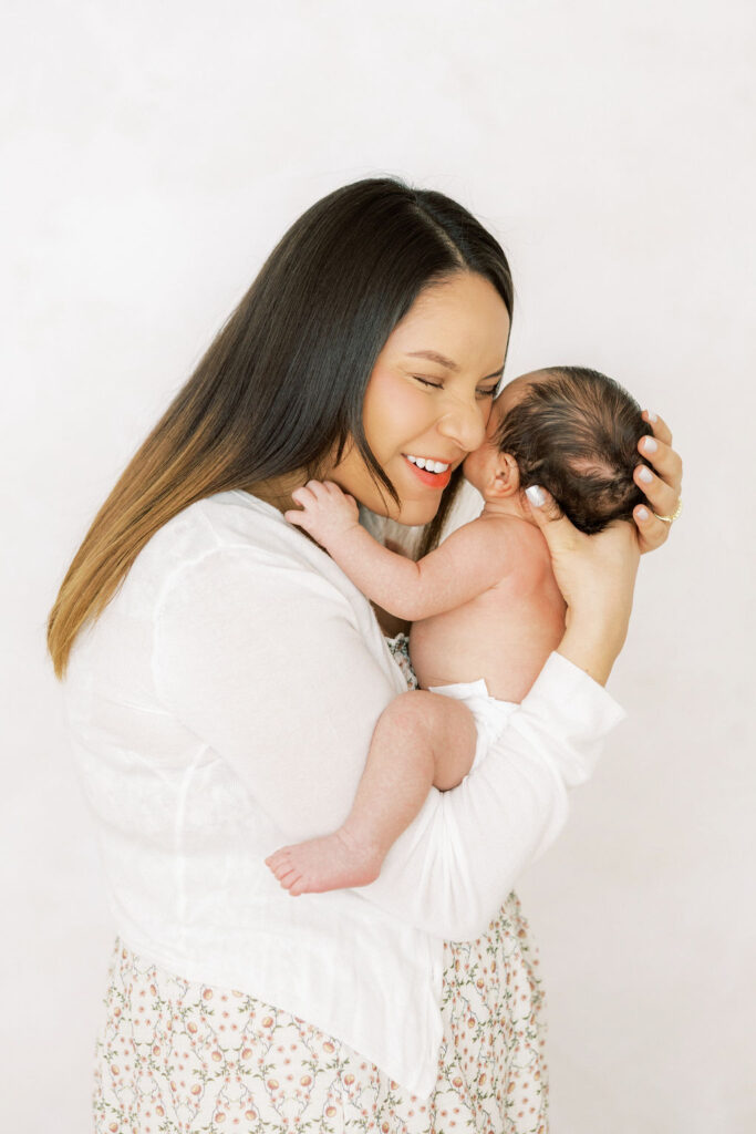 Mother kissing and smiling at her newborn baby during a natural family moment