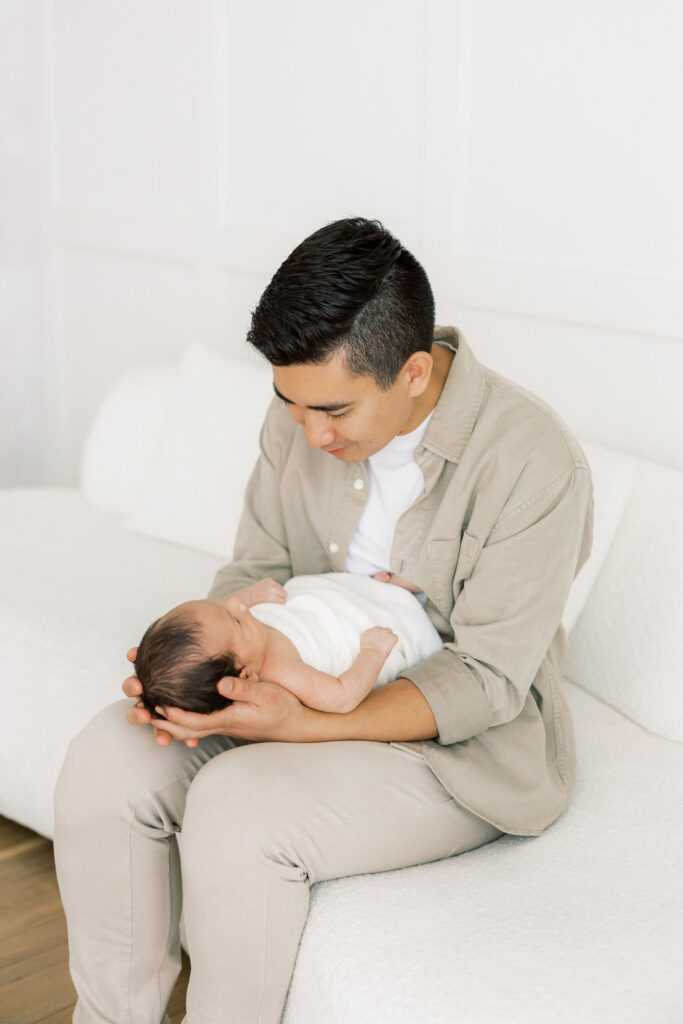 Dad looking down at his newborn baby during a studio session