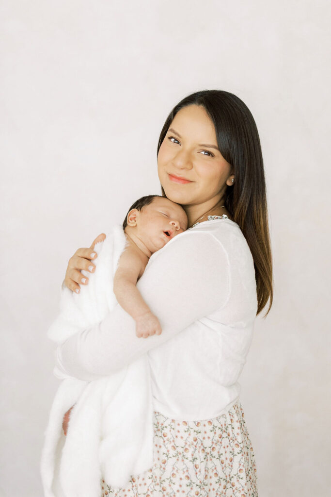 Smiling mom cuddling her newborn baby during a lifestyle session