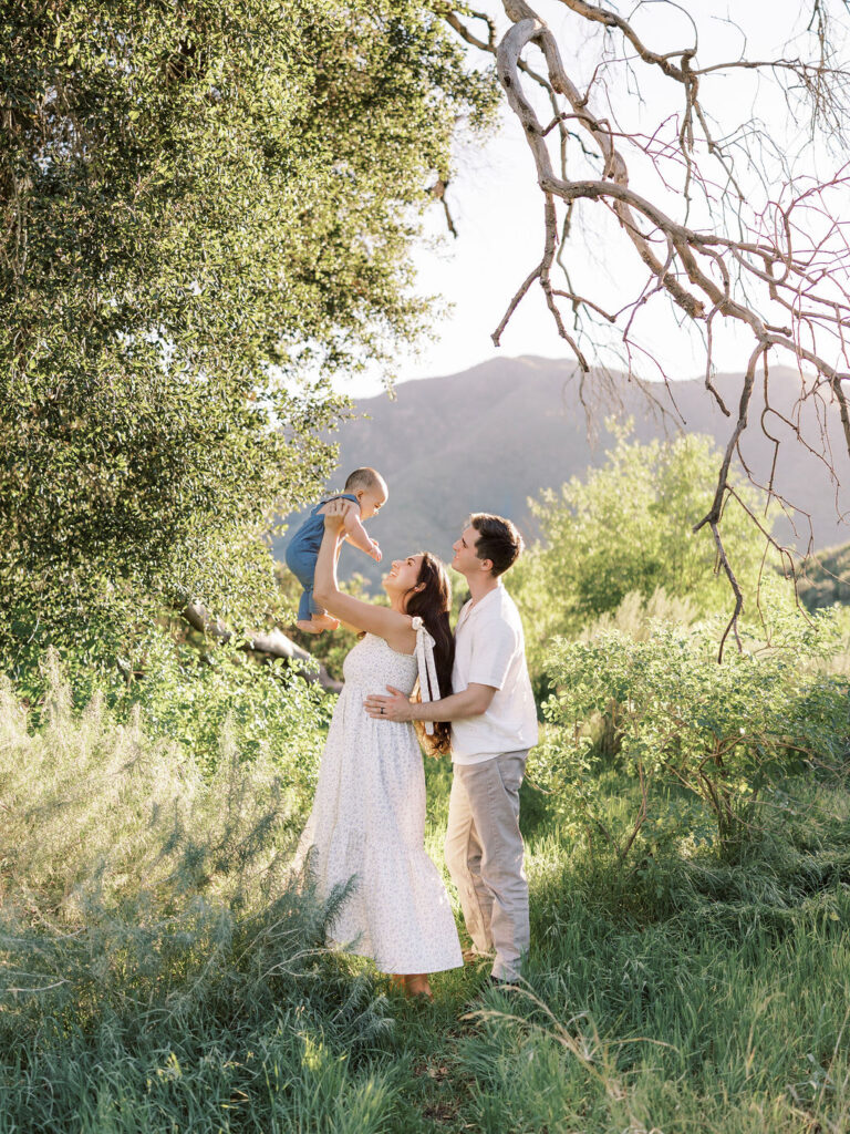 Family playing with their young child during natural family photos with kids in Santa Clarita