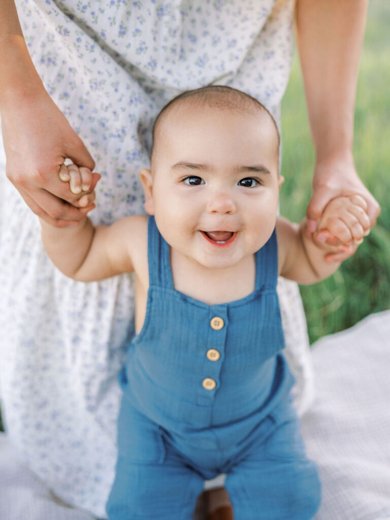 Smiling baby holding parents’ hands during a natural family photo session in Santa Clarita