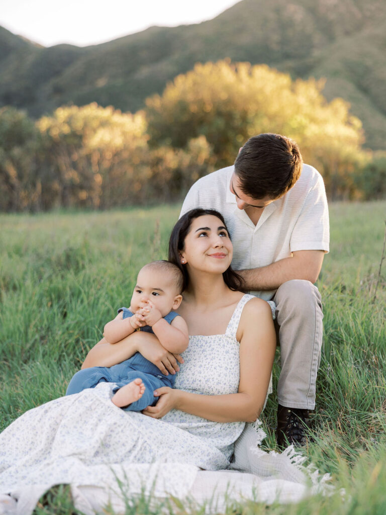 Family of three sharing a quiet moment in a grassy field