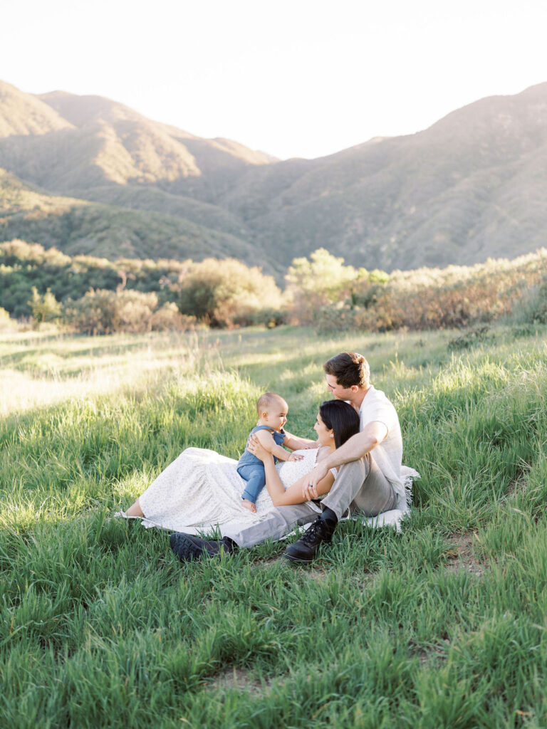 Mom and dad sitting with their baby in the grass