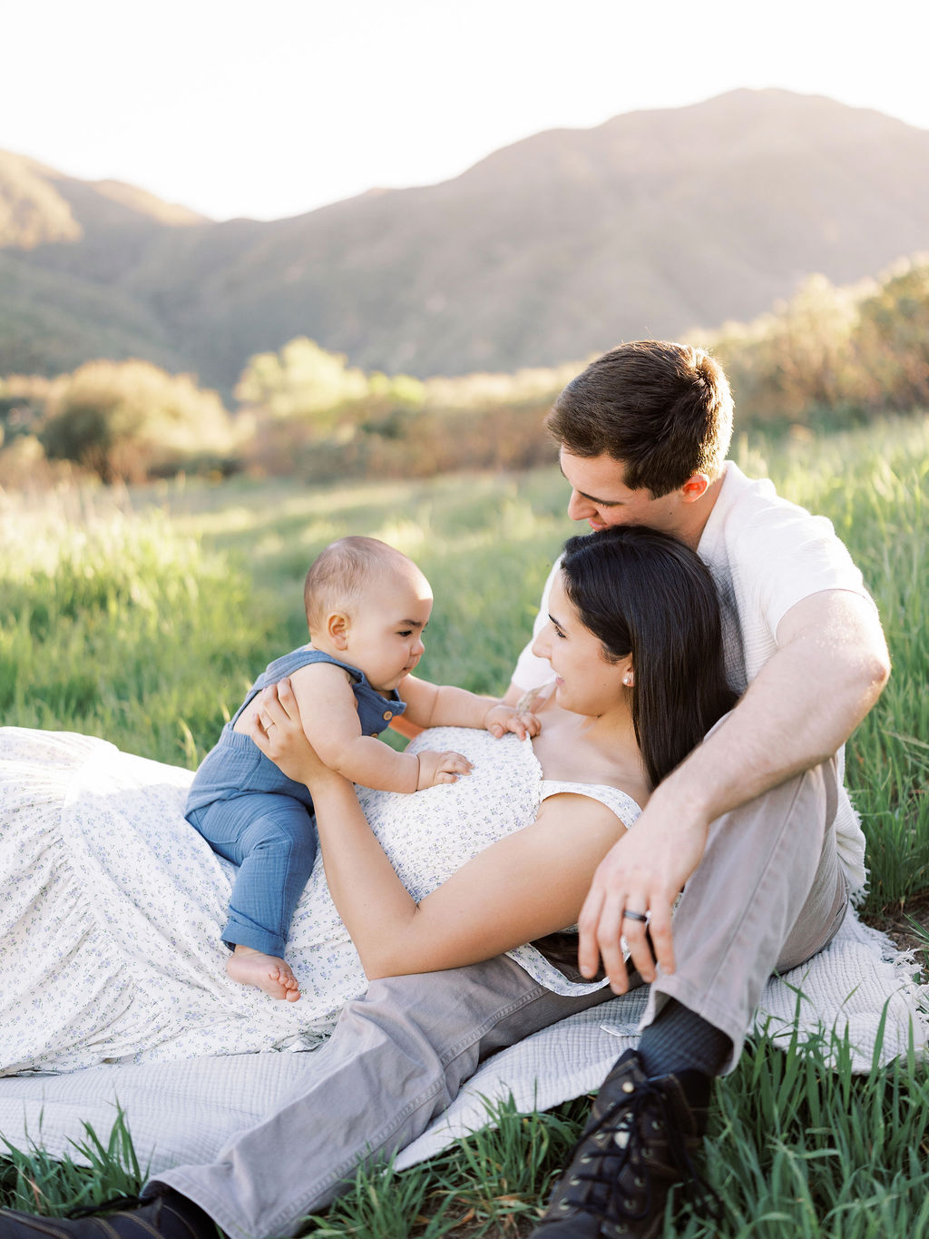 Parents sitting with their baby in a field during natural family photos in Santa Clarita