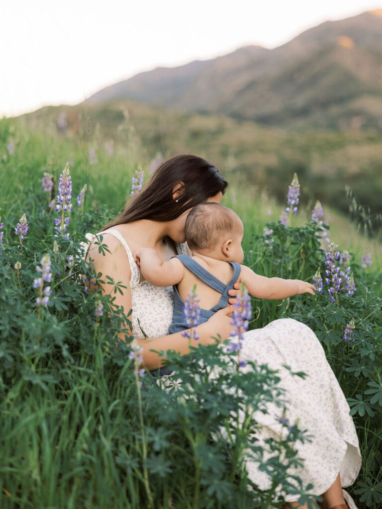 Mom cuddling her baby in a wildflowers field during a relaxed spring family photo session