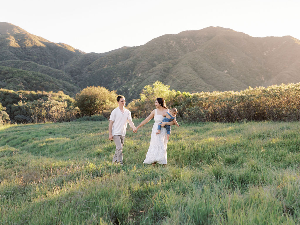 Family walking together through a field during natural family photos with a child