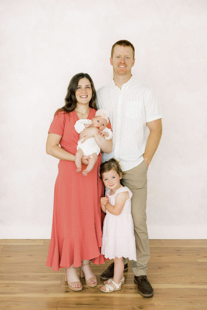 Family of four standing together with their newborn baby girl during studio newborn photos in Santa Clarita.