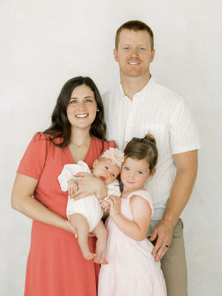 Family of four posing together with their newborn baby girl during newborn photos in Santa Clarita.