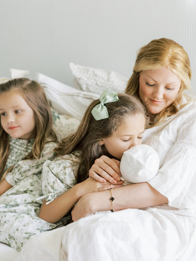 Mom holding her newborn while siblings gather close during a natural family moment