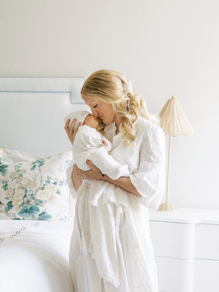 Mom in a white dress kissing her newborn baby during a soft, natural Santa Clarita newborn photography session.