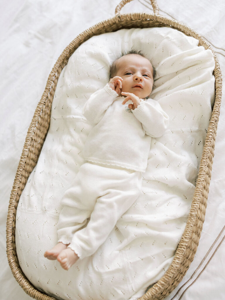 Newborn baby resting peacefully in a woven bassinet