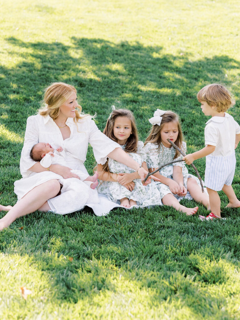 Mom outdoors with her children during newborn photos with siblings