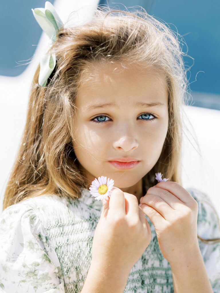 Little girl photographed during a newborn session with siblings and holding flowers