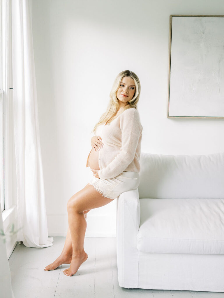 Expecting mom reclining with her hands on her belly during maternity photo session preparation