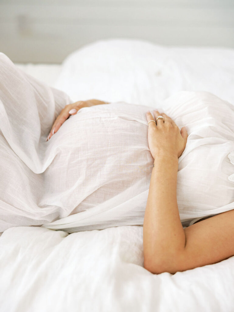 Expecting mom relaxing with flowers on her belly while preparing for her maternity photo session in Santa Clarita