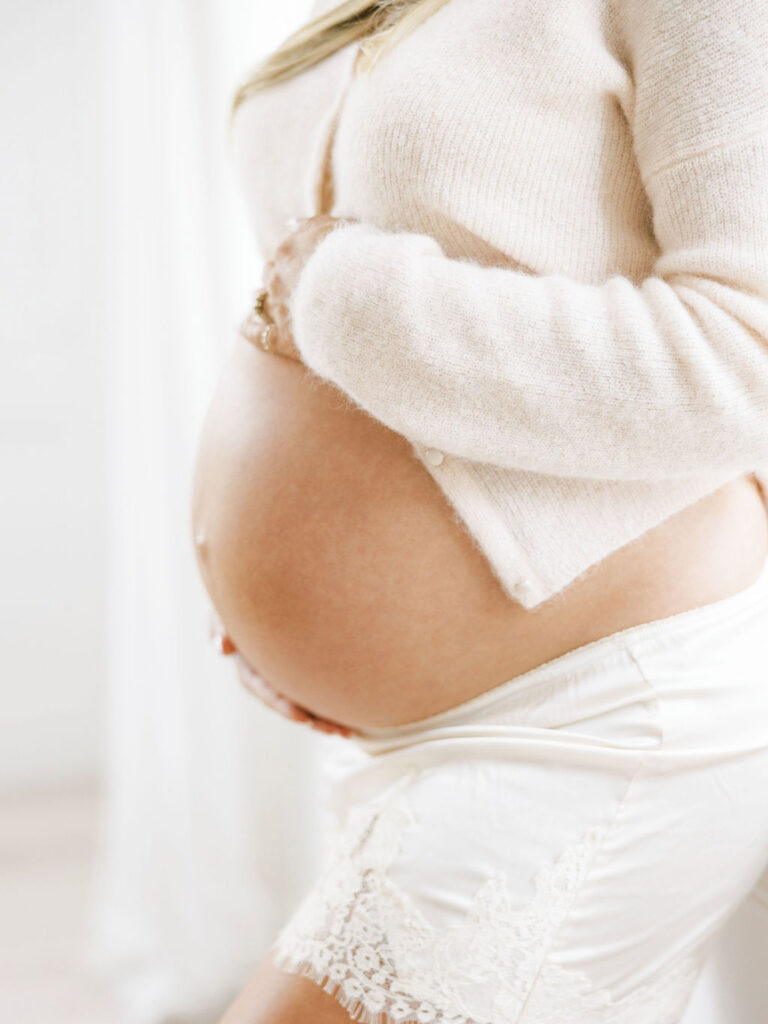 Close detail of a baby bump in a soft sweater showing simple maternity session styling
